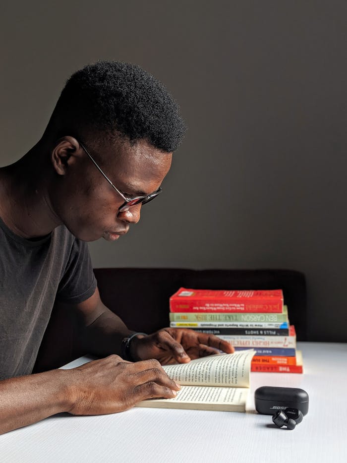 gallery-4 Young man studying intently with books in library setting.