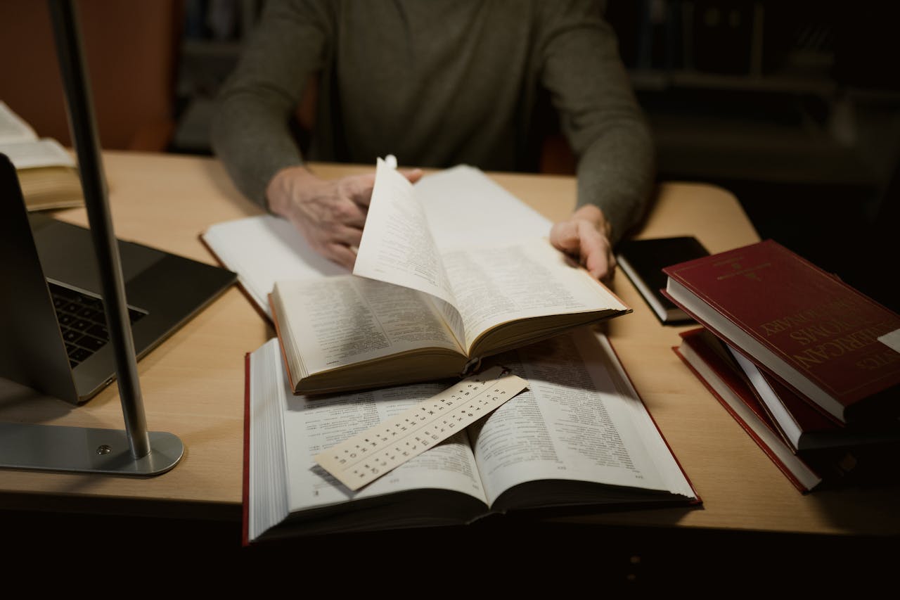 A person engrossed in studying with open books on a desk.
