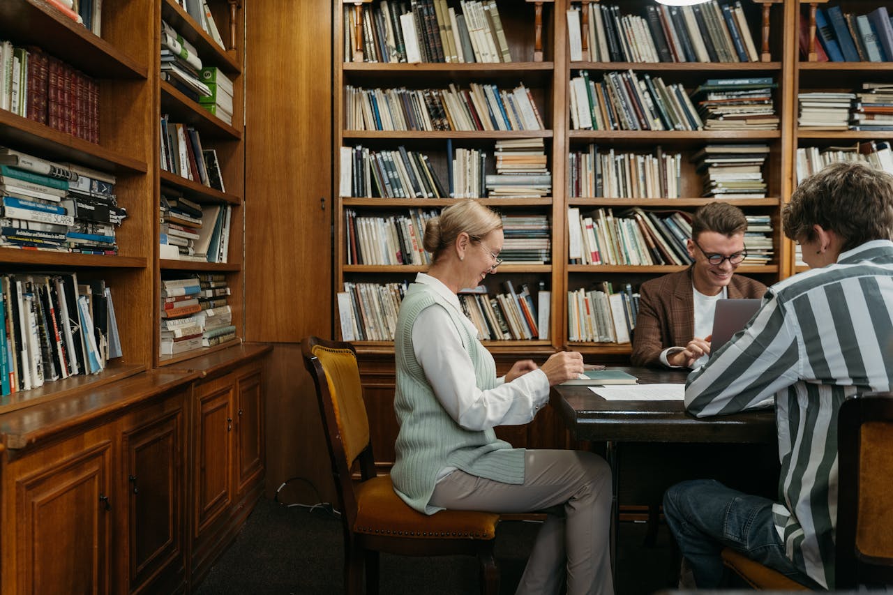 services-04 Group of students studying together in a cozy library setting with bookshelves around.